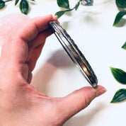 Vintage sterling silver compact mirror from Towle Silversmiths held in hand with green foliage background