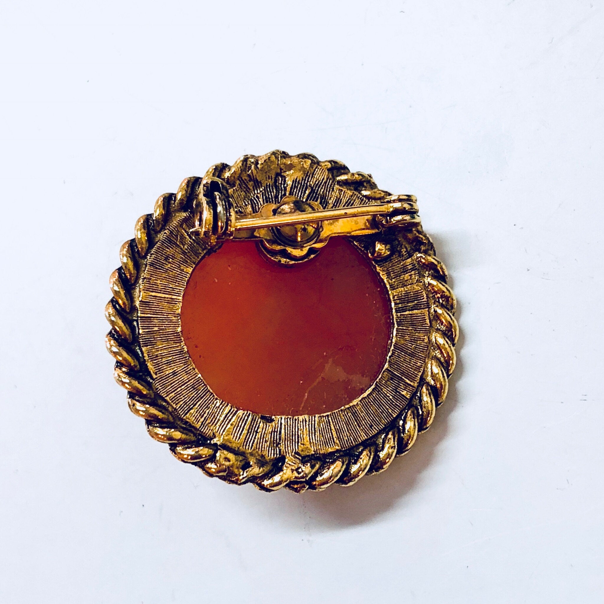 Vintage orange cameo brooch with gold tone round frame and twisted rope border design, Victorian era jewelry pin.