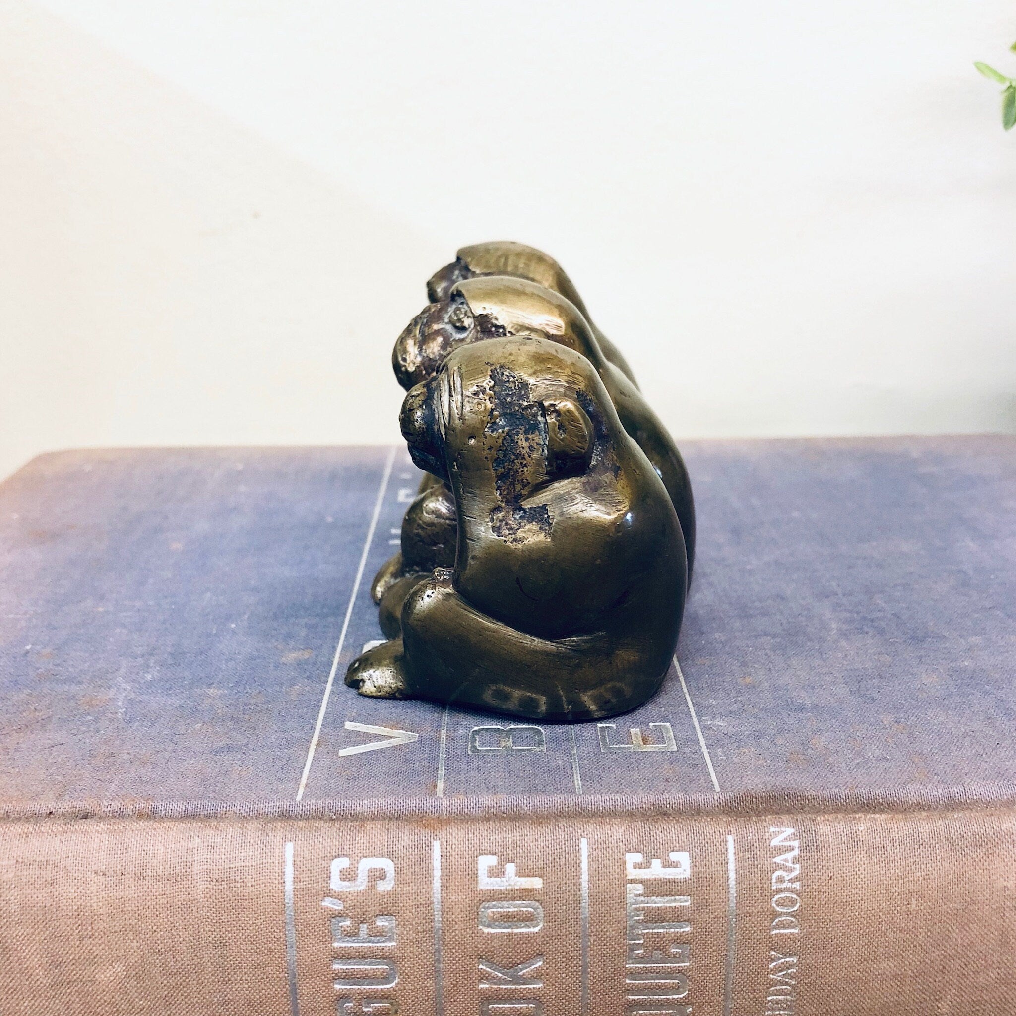Brass figurine of three monkeys posed in "see no evil, hear no evil, speak no evil" poses on old book