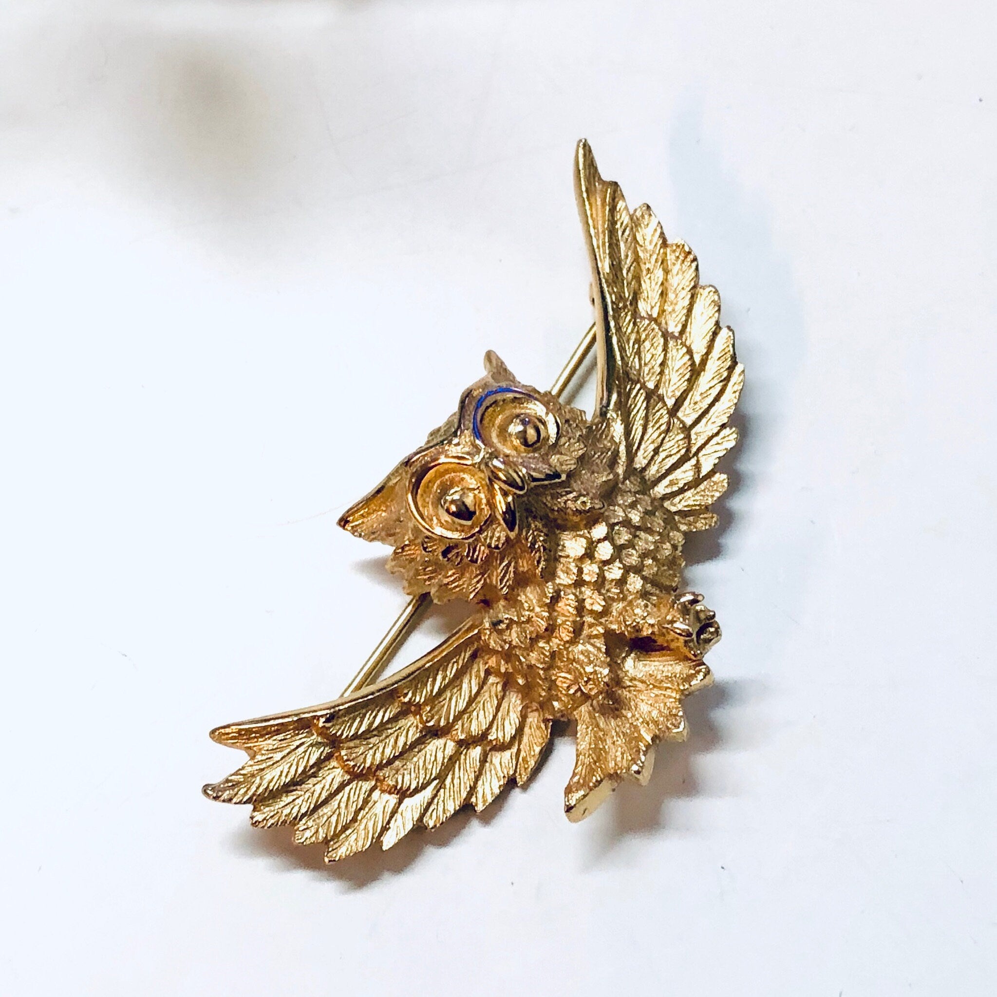 Vintage gold-toned owl brooch with intricate wing and feather details, resembling a Trifari design, suitable as a statement piece of bird or animal-themed jewelry.