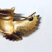 Vintage gold-toned owl brooch with spread wings, marked 'Trifari' on the back, displayed on a white background.