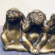 Three brass monkey figurines depicting "see no evil, hear no evil, speak no evil" proverb, sitting in poses with hands covering eyes, ears, and mouth, tarnished vintage home decor.