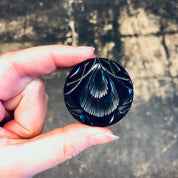 Vintage black carved round Bakelite mourning brooch from the 1930s held in hand