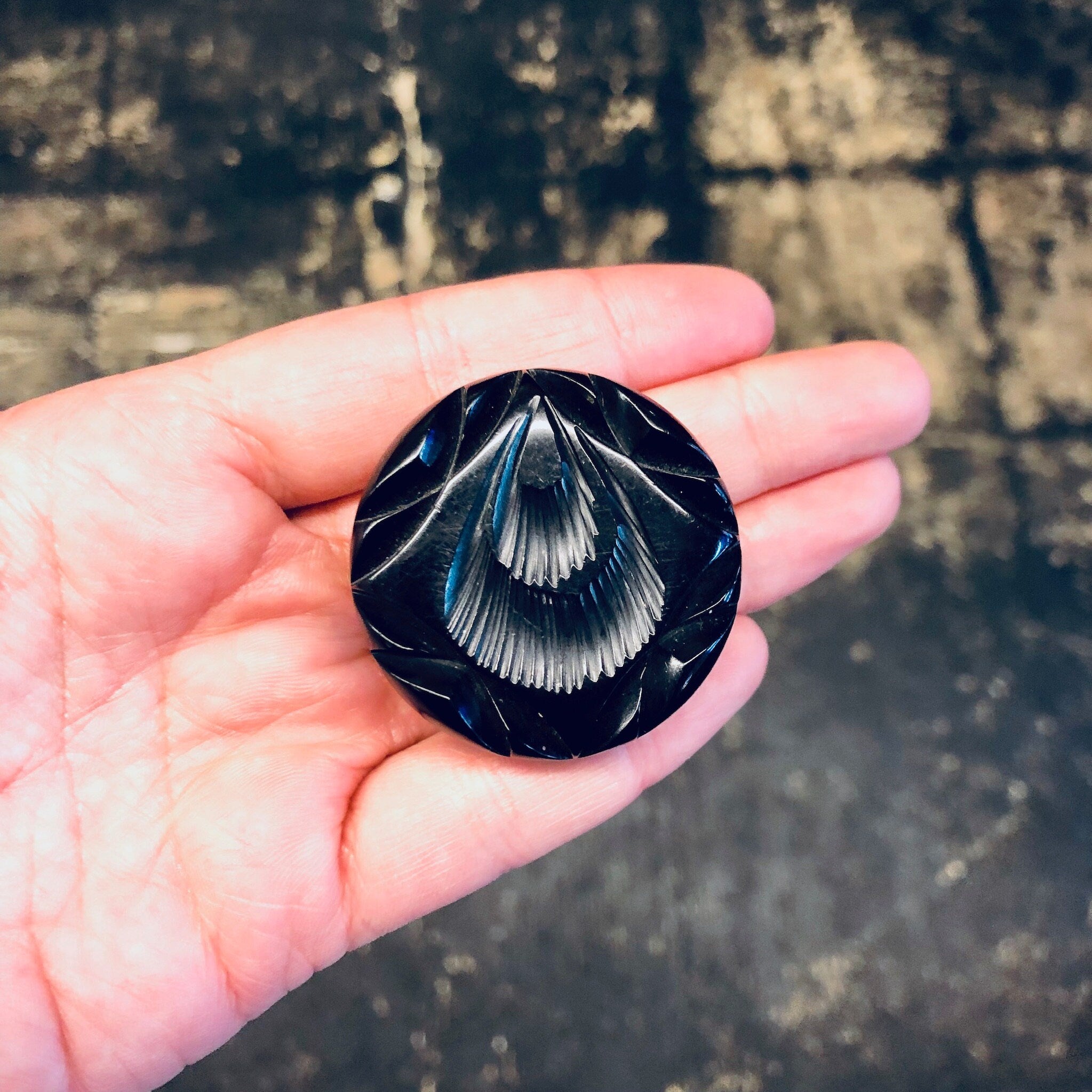 Vintage black carved Bakelite mourning pin brooch from the 1930s held in palm of hand