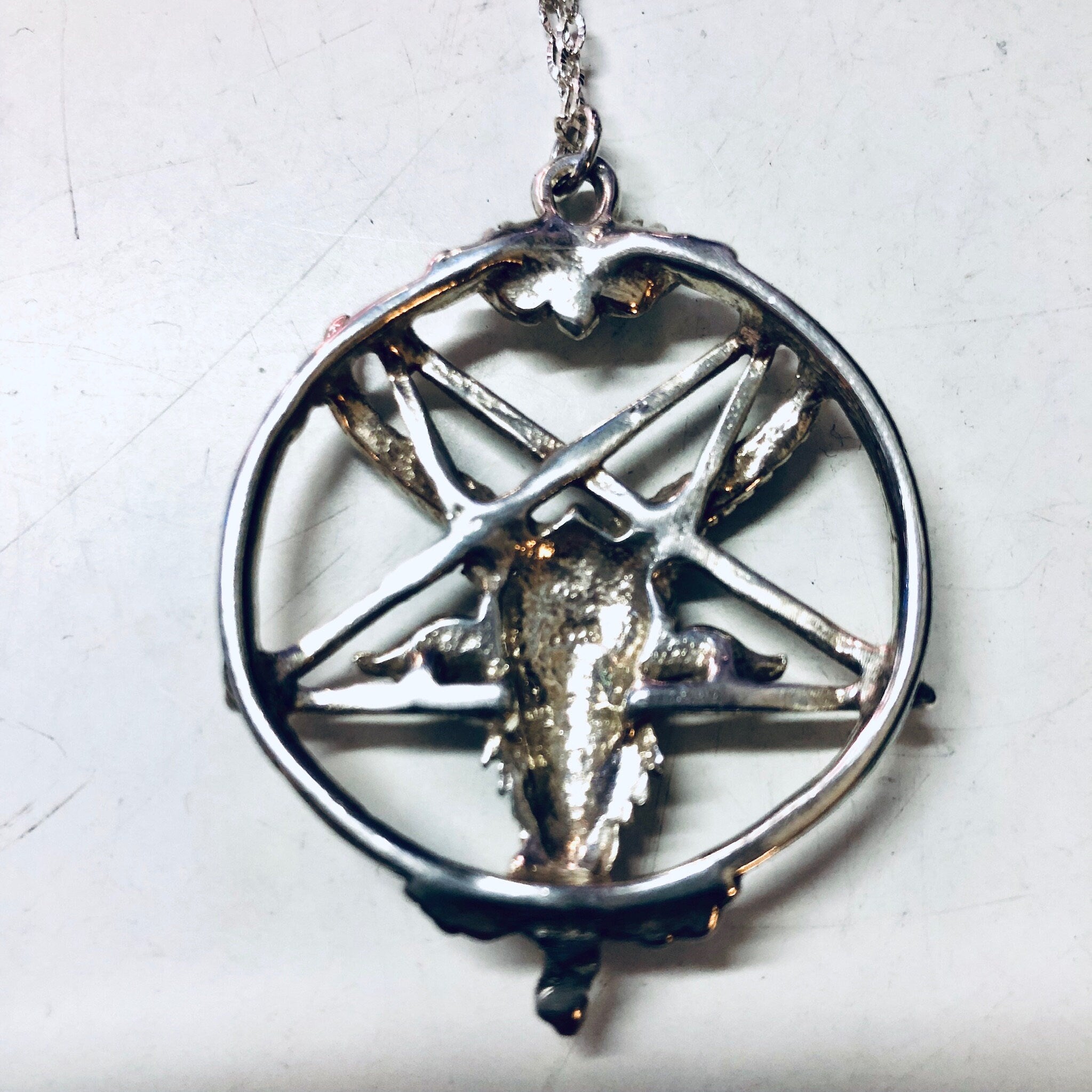 Alt text: Vintage silver necklace featuring a pentagram pendant with a goat head figure, dangling from a delicate chain, Gothic jewelry perfect for Valentine's Day or witch-inspired looks.