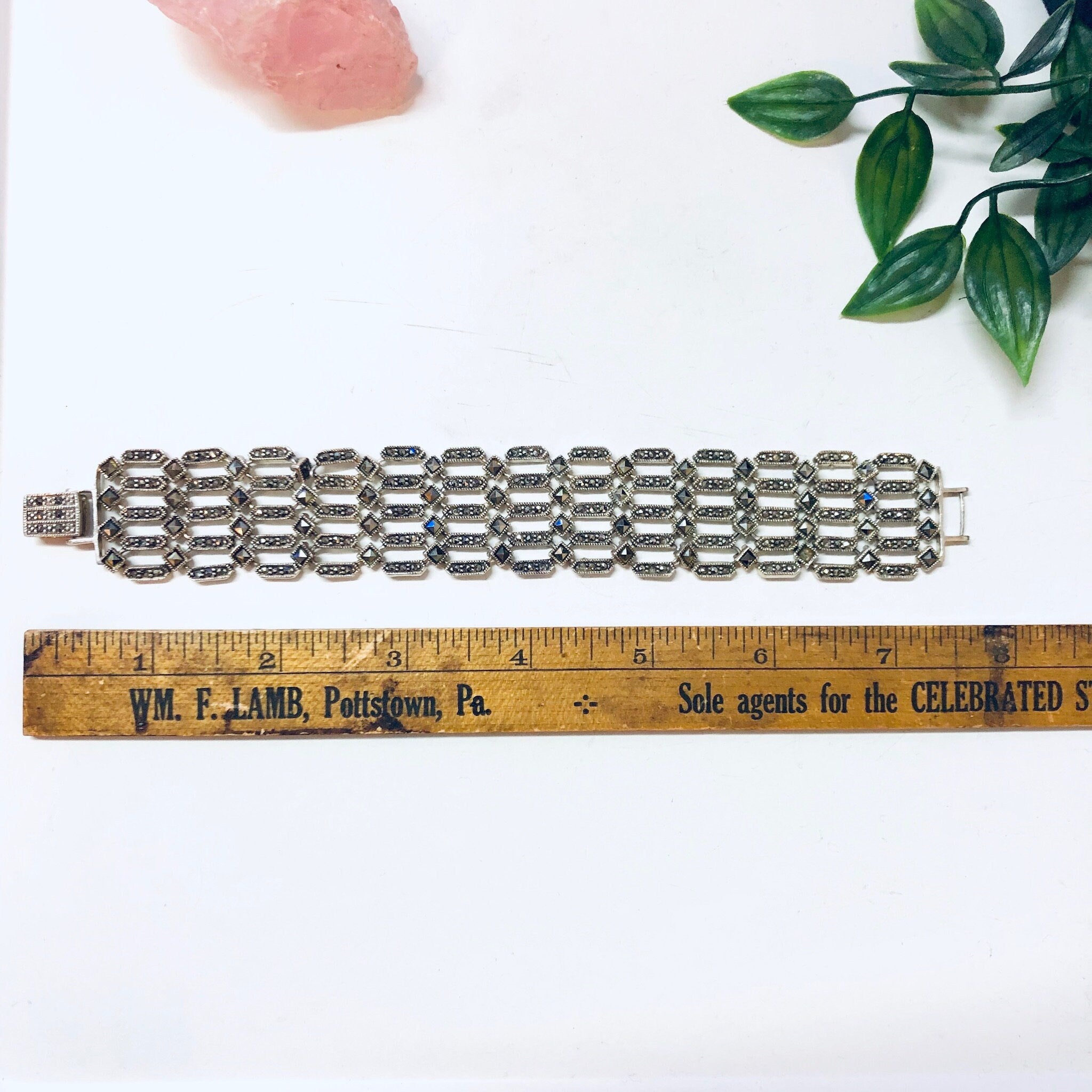 Vintage sterling silver marcasite link bracelet displayed with ruler, ad and greenery