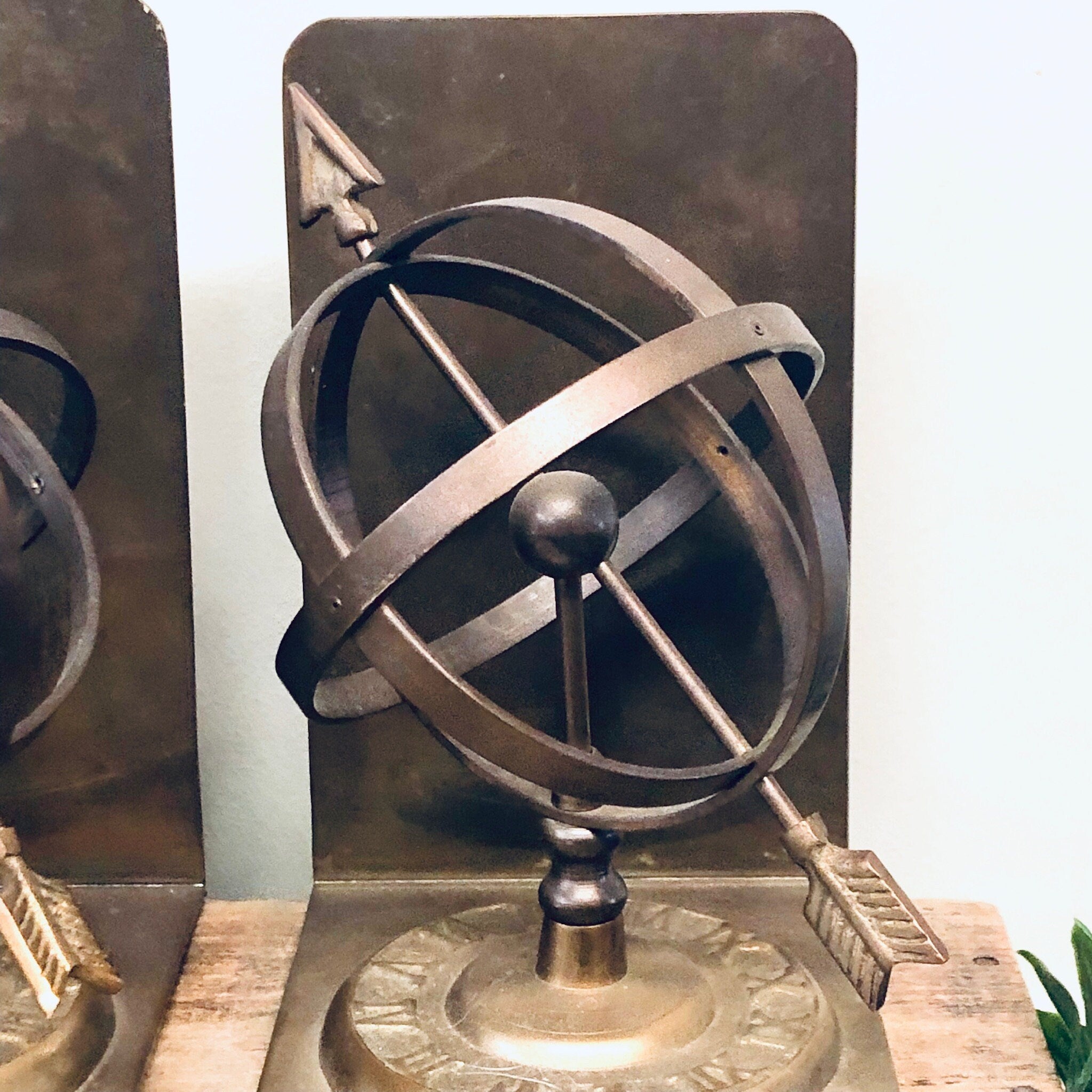 Vintage brass spherical sundial bookends with Roman numerals, perfect for library decor or unique home decor on a bookshelf.