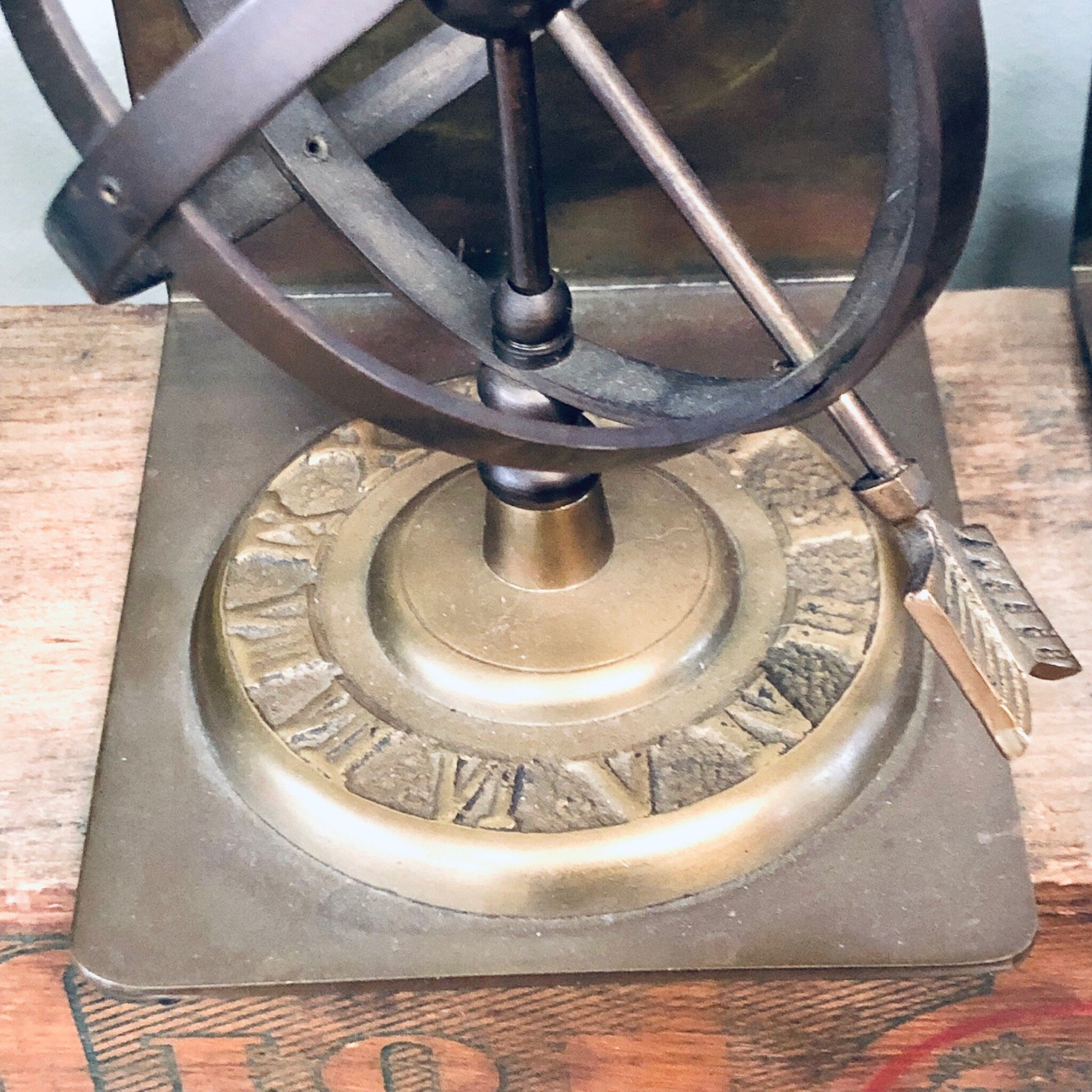 Antique brass spherical bookends with sundial and roman numerals on wooden surface