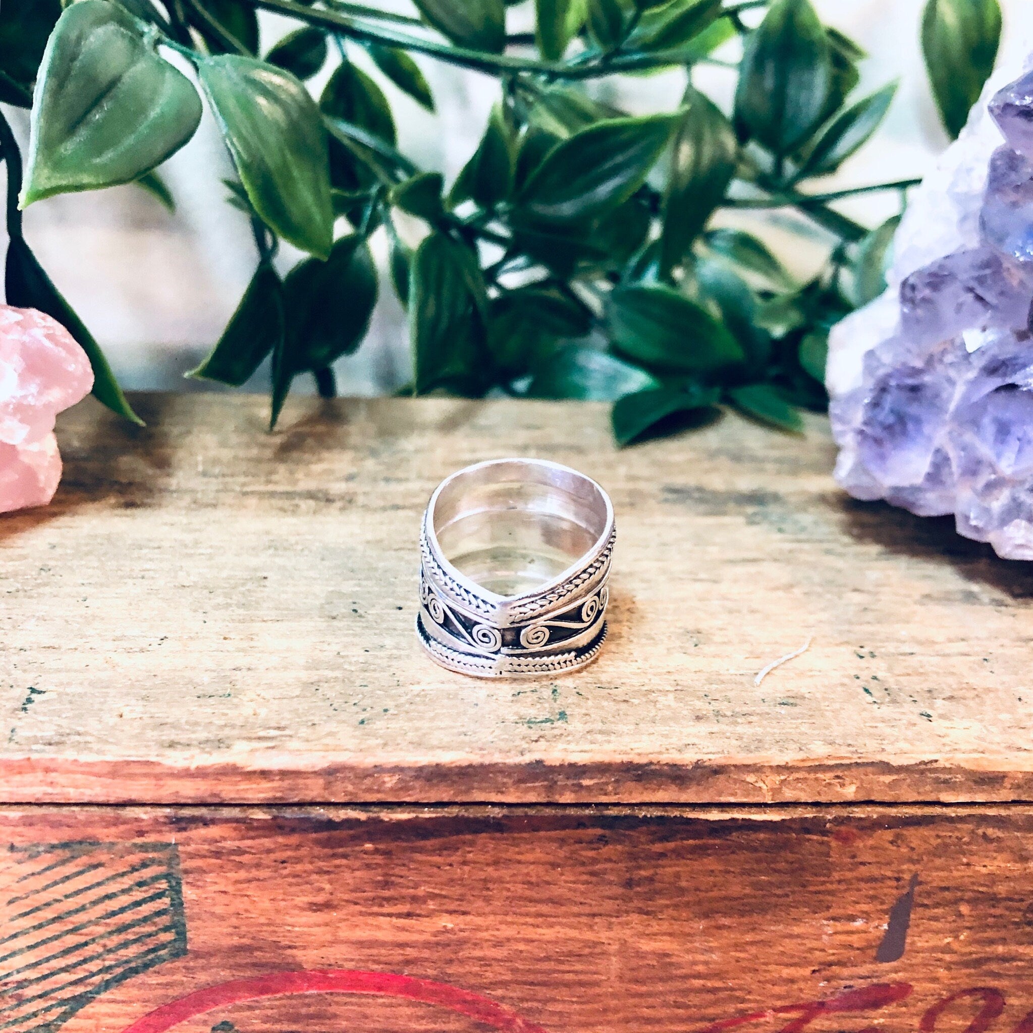 Vintage silver swirl band ring on wood table with crystals and plants