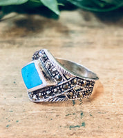 Vintage silver marcasite ring with turquoise stone, 925 sterling, diamond-shaped, sparkly statement jewelry on wooden background.