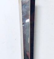 The image shows a close-up view of a metal candlestick or candle holder. The candlestick appears to be made of polished sterling silver, with a thin vertical shape. The silver has some scratches and patina, indicating it is a vintage or antique piece. The candlestick is photographed against a plain white background, emphasizing its shiny metallic surface and slender form.