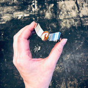 Hand holding a vintage silver cuff bracelet with a red natural stone against a grungy textured background