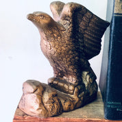 Antique ceramic eagle bookends with detailed sculpted feathers in a brown and gold color scheme, perched on a wooden base, adding a vintage decorative touch to bookshelves or library decor.