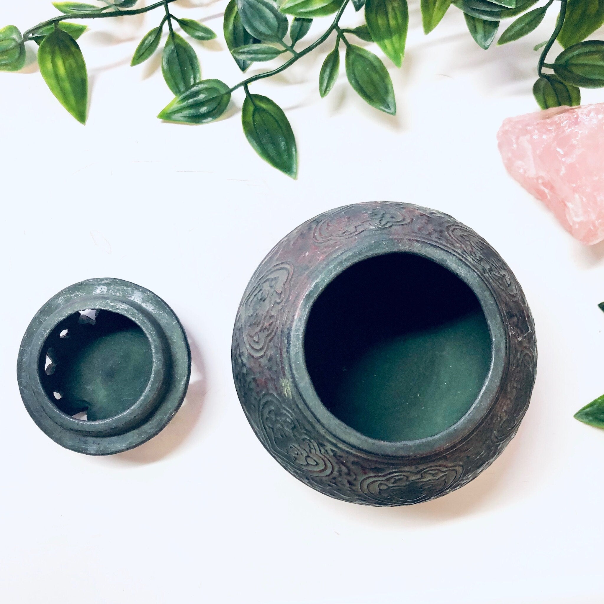 Vintage green ceramic incense burner with floral design and lid, surrounded by greenery and pink stones, unique housewarming gift idea.
