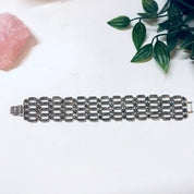 Vintage sterling silver marcasite link bracelet on white background with rose quartz and greenery accents