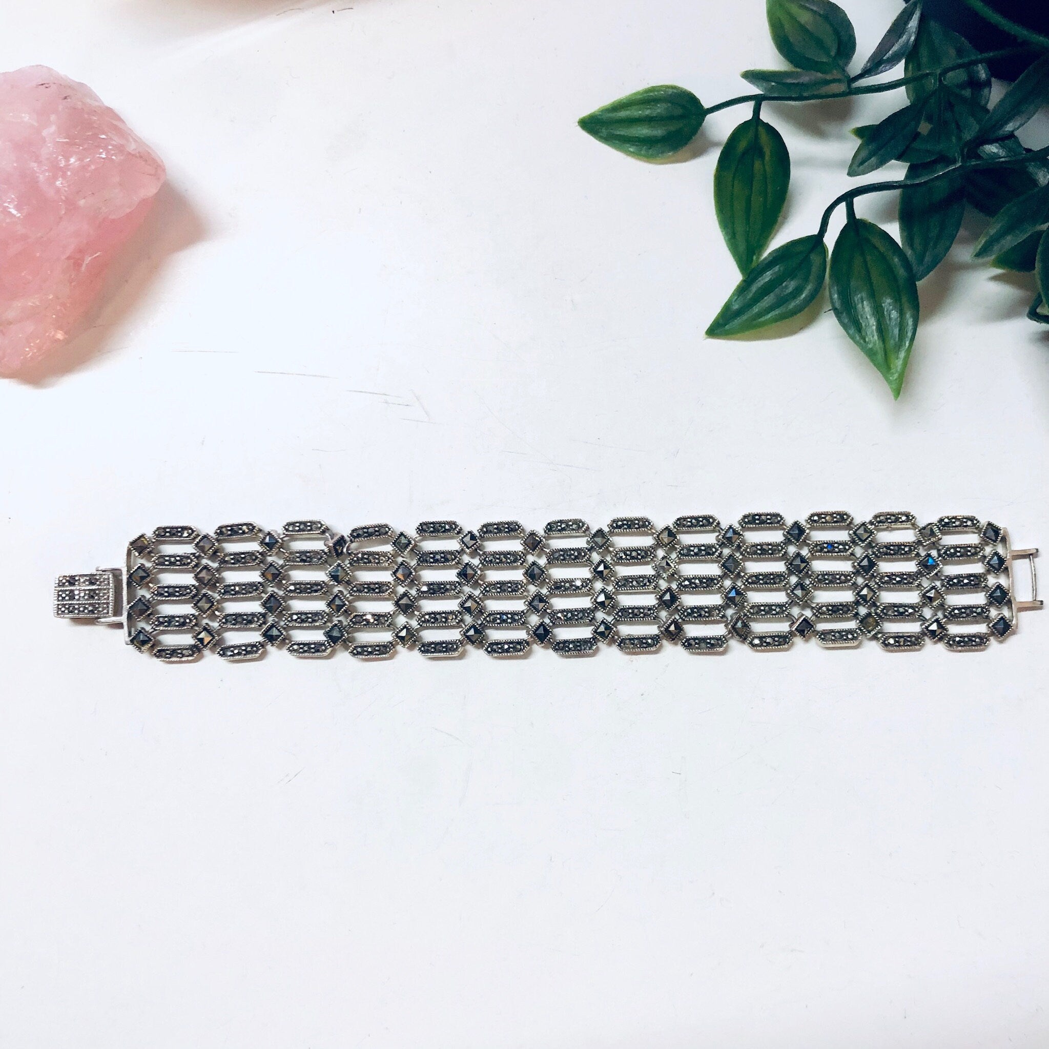 Vintage sterling silver marcasite link bracelet on white background with rose quartz and greenery accents