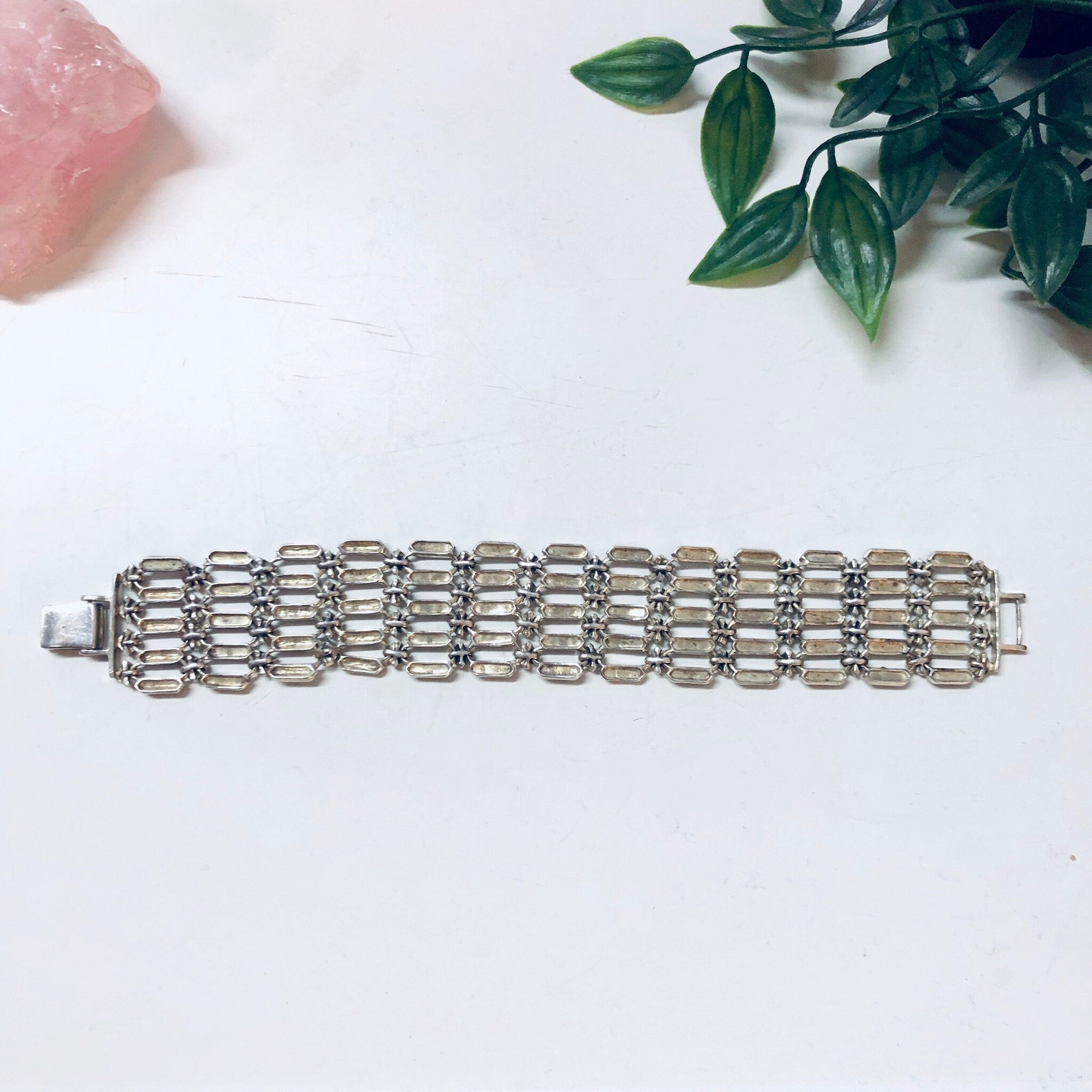 Vintage sterling silver marcasite link bracelet on white background with pink quartz and green leaves