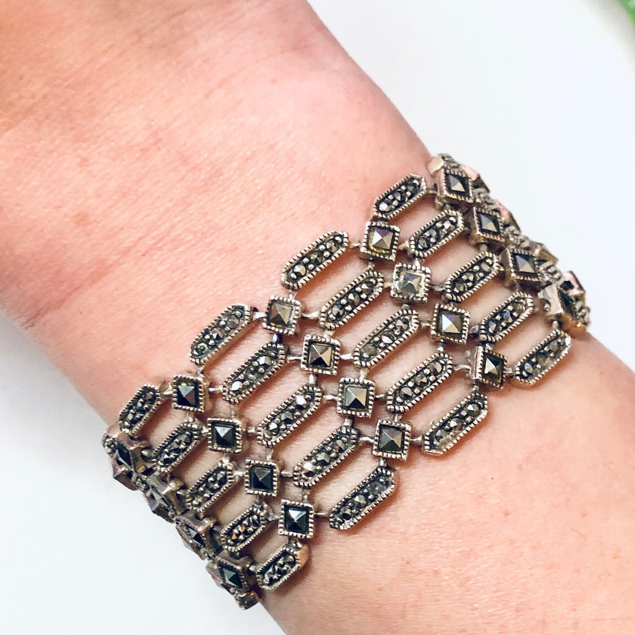 Alt text: Vintage sterling silver marcasite link bracelet on a person's wrist, featuring a geometric design with multiple rows of rectangular silver links adorned with small marcasite stones, creating an elegant statement jewelry piece suitable as a Valentine's Day gift.