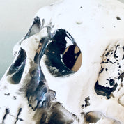 Abstract navy and gray painting resembling a human skull with eye sockets against a white textured background