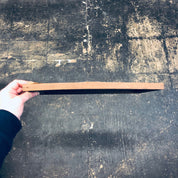 Hand holding a wooden ruler on a grungy, weathered concrete surface