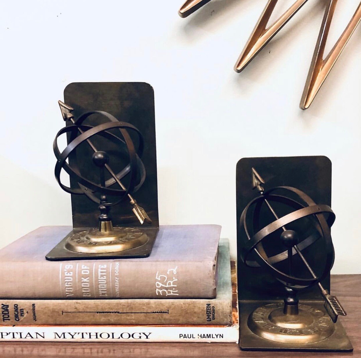Brass armillary sphere bookends with Roman numerals on vintage books, geometric modern home decor