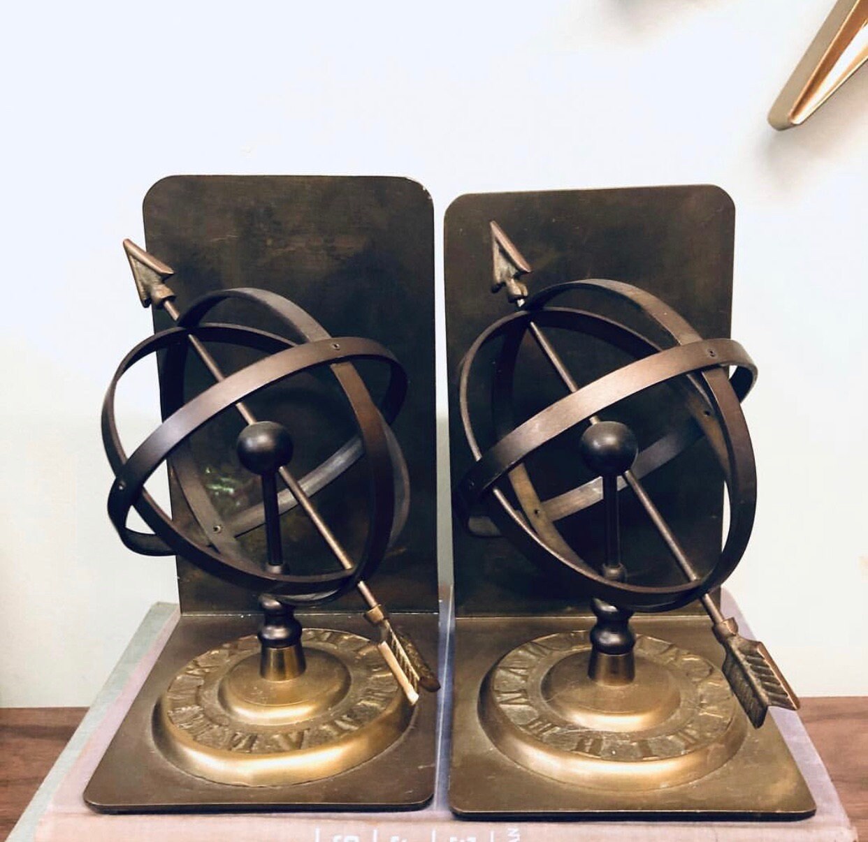 Pair of vintage brass armillary sphere bookends with Roman numeral dials on antique metal bases, unique library or bookshelf decor