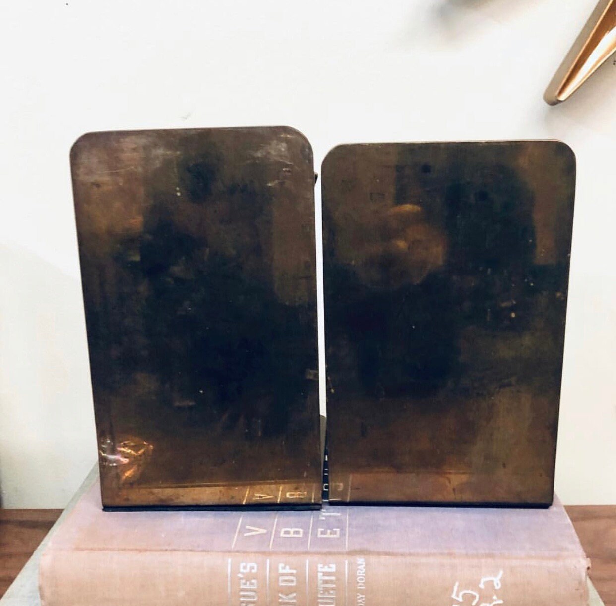 Pair of vintage brass bookends featuring sundial design with Roman numerals, ideal for library decor or as a unique home accent on bookshelves.