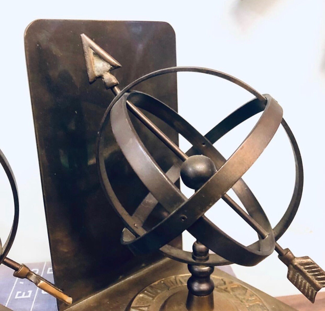 Vintage brass sundial bookends with spherical design and Roman numerals, perfect for library decor or unique home accents on a bookshelf.