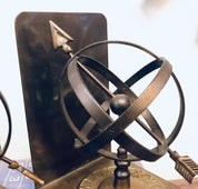 Vintage brass sundial bookends with spherical design and Roman numerals, perfect for library decor or unique home accents on a bookshelf.