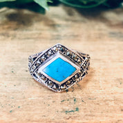 Vintage silver marcasite ring with turquoise stone, statement diamond-shaped 925 sterling sparkly ring on wooden surface.