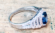 Vintage silver ring with blue stone and faux diamonds, marked "BYJ 925", on textured background