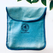 Vintage teal velvet cigarette case or business card holder with Mother of Pearl inlay from Bailey Banks and Biddle, Philadelphia, resting on white surface with green leaves in background.