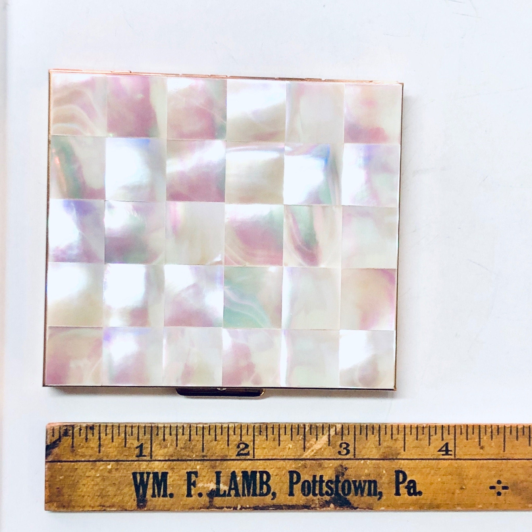 Vintage mother of pearl cigarette case or business card holder with pink and white checkerboard pattern, shown with a wooden ruler for scale.