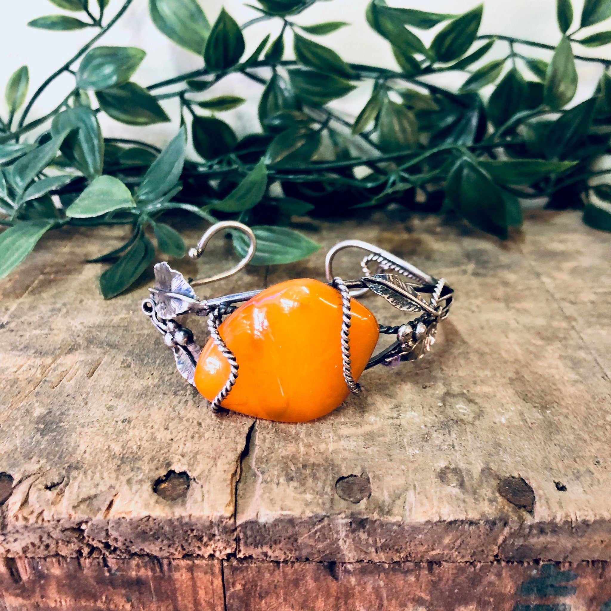 Vintage butterscotch amber bracelet with silver leaf details on wooden surface, 925 stamped statement cuff jewelry