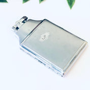Vintage silver Ronson Mastercase cigarette holder and lighter with monogrammed initials, against a white background with green leaves at the top of the frame.