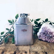 Vintage Ronson silver cigarette lighter case on wooden surface with leaves and purple geode crystal.