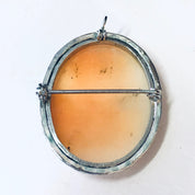 Vintage silver-toned cameo brooch pin with a round orange and peach colored cameo pendant set in an ornate circular frame, antique costume jewelry from the Victorian era