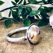Vintage Lunt Sterling silver baby rattle on rustic wooden surface with green foliage in background