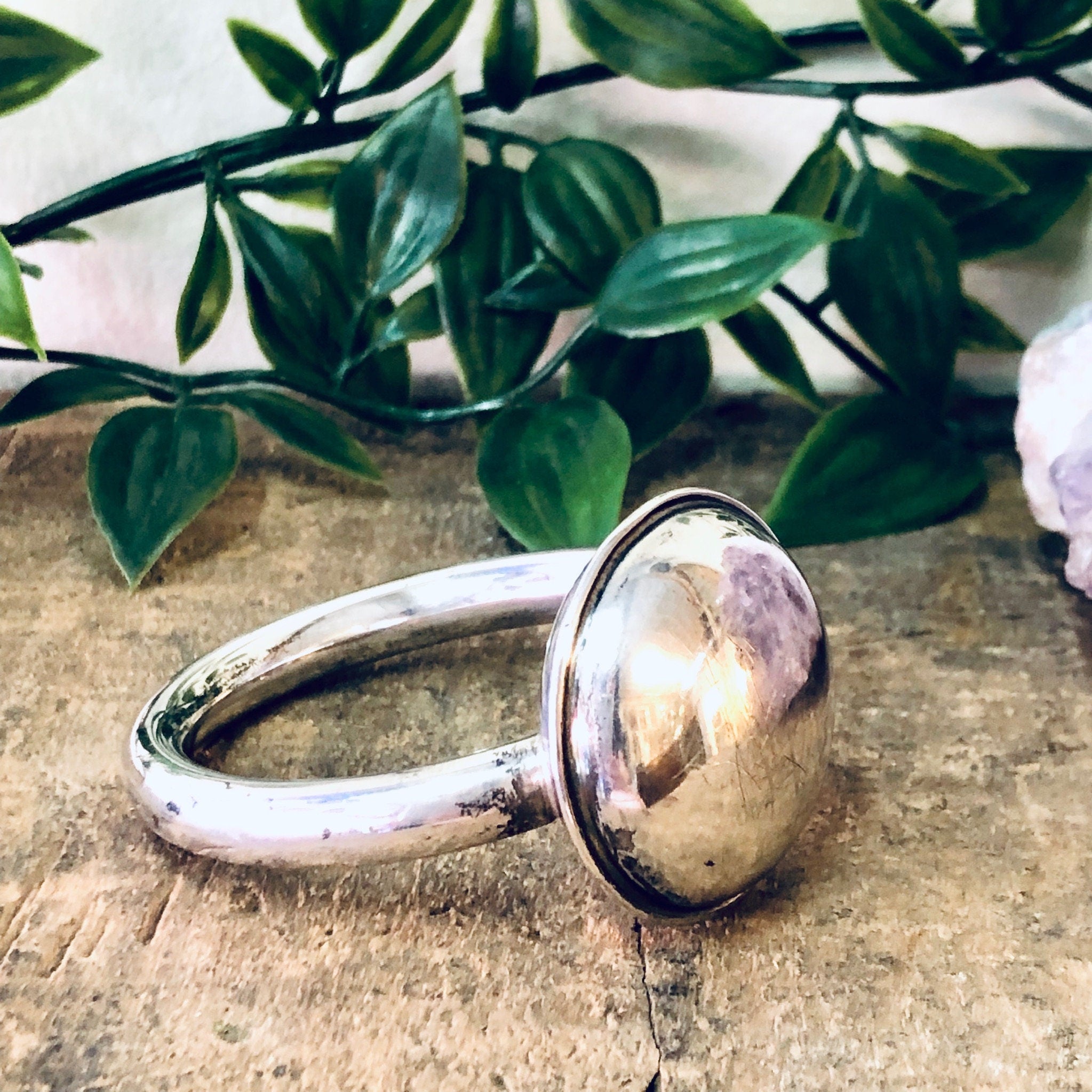 Vintage Lunt Sterling silver baby rattle on rustic wooden surface with green foliage in background