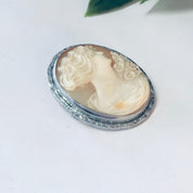 Vintage cameo brooch pin with silver toned setting against a white background
