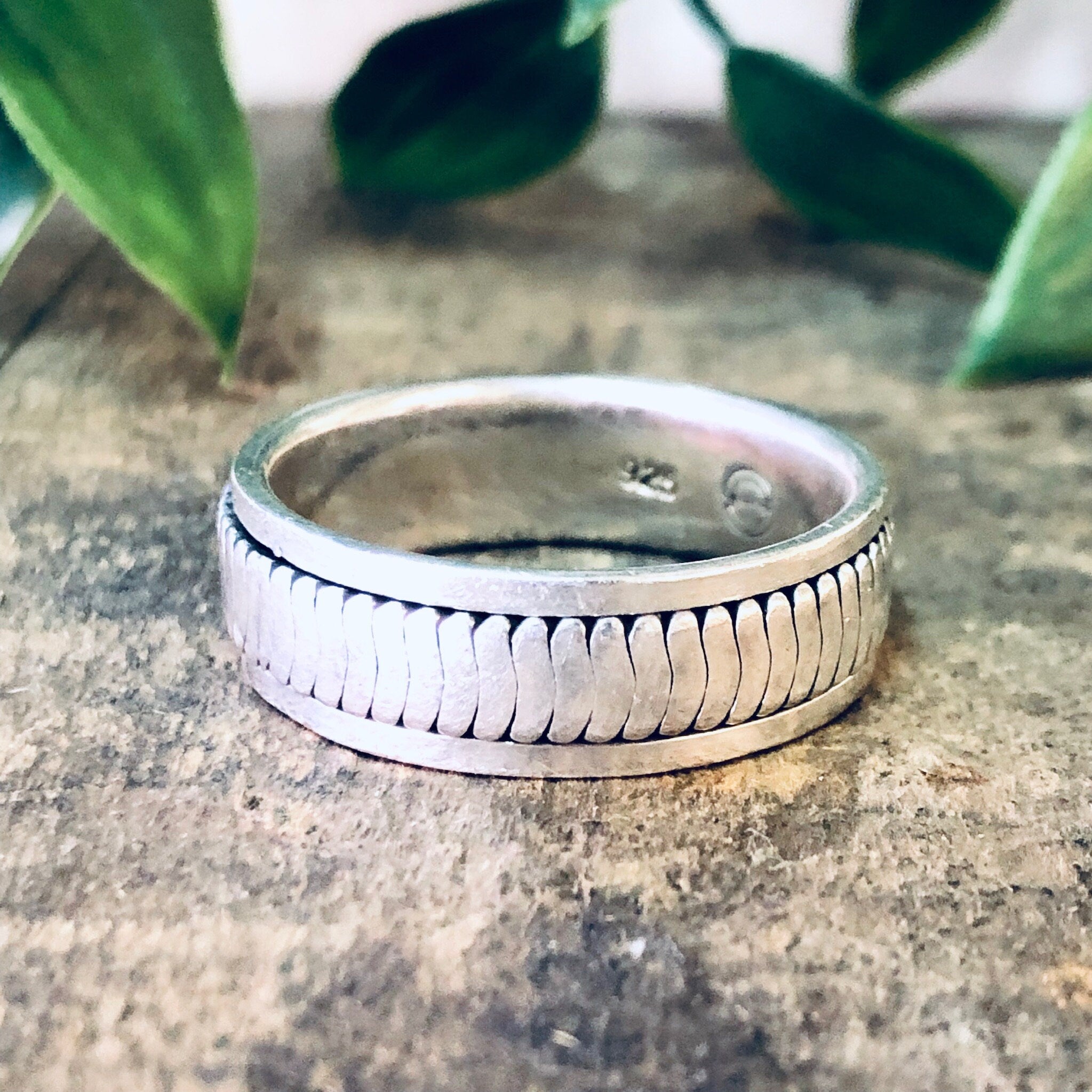 Vintage silver spinner meditation ring on rustic stone surface with green leaves in background