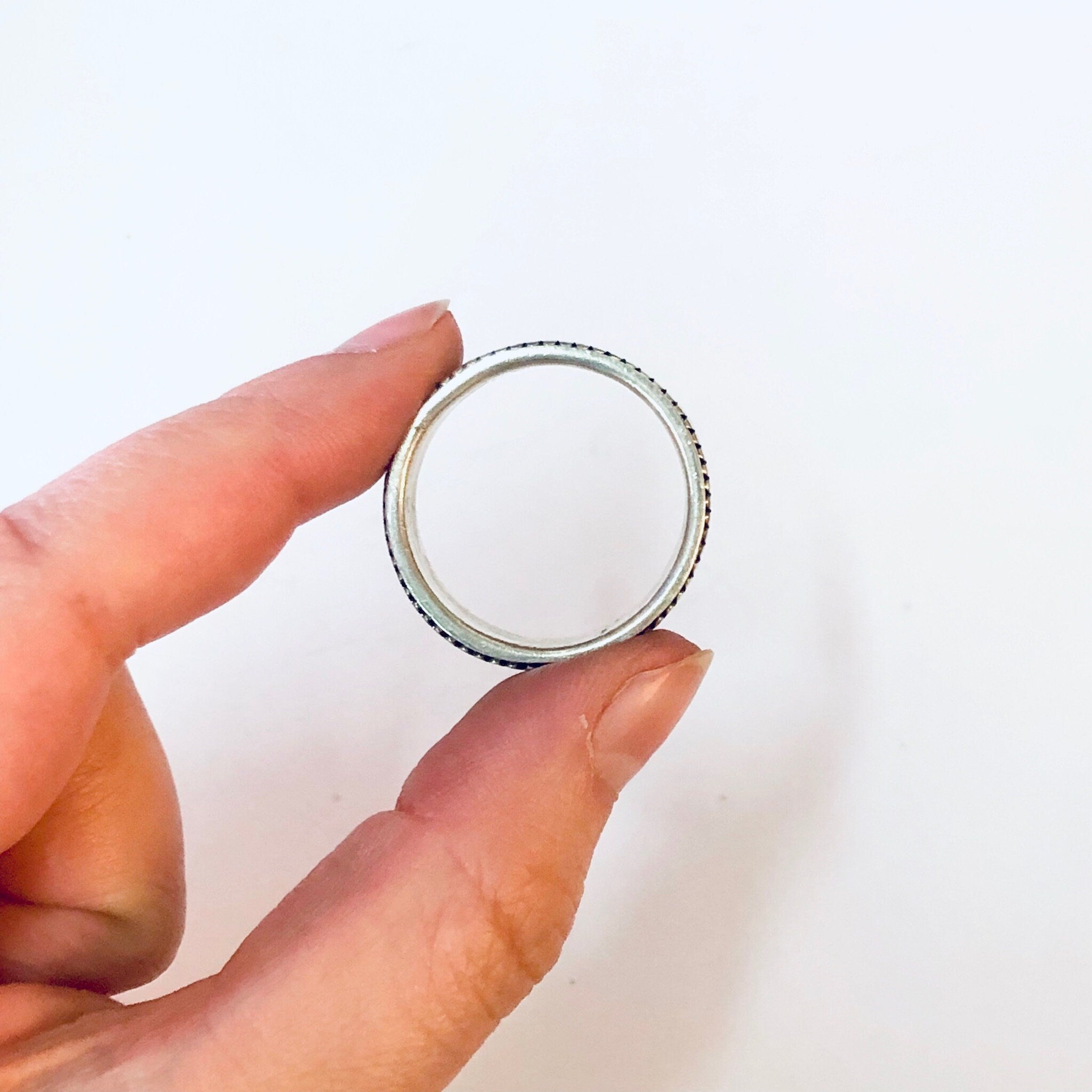 Fingers holding a large vintage silver spinner meditation ring against a white background.