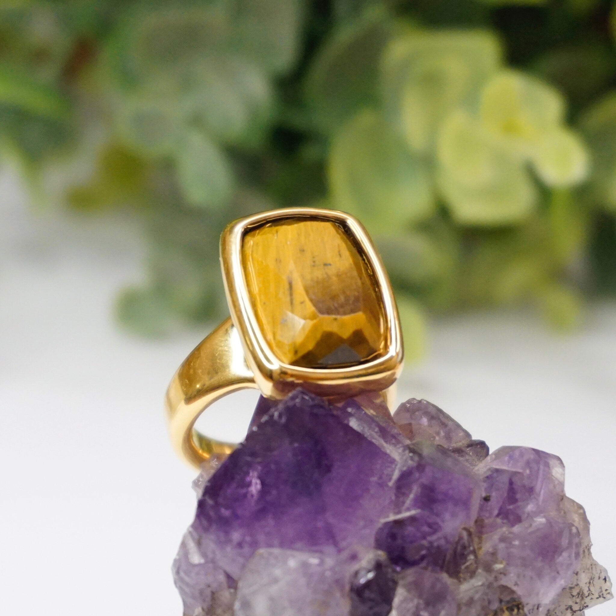 Vintage 14K gold tiger's eye ring featuring a large, rectangle cut tiger's eye stone set in a shining gold band, handcrafted in Italy using a 14K gold over resin technique by Milor. The semi-transparent brown tiger's eye gem is displayed against a beautiful purple crystal geode.