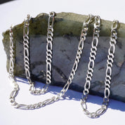Vintage sterling silver Figaro chain necklaces, 34 inches long, made in Italy. The chains are layered on a grey stone surface.