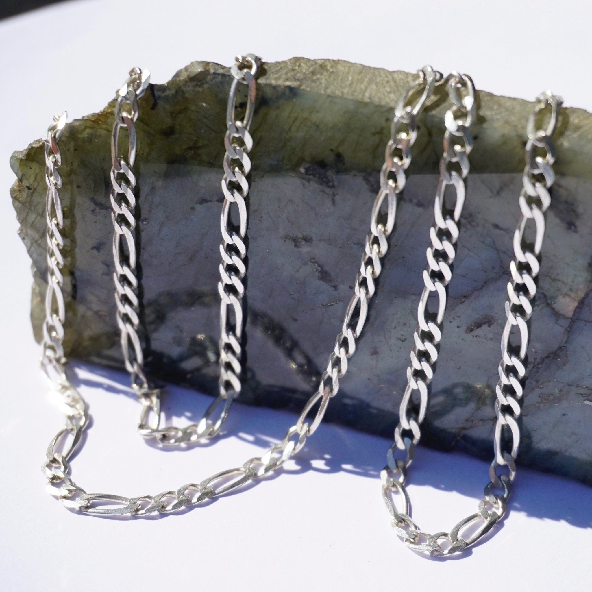 Vintage sterling silver Figaro chain necklaces, 34 inches long, made in Italy. The chains are layered on a grey stone surface.