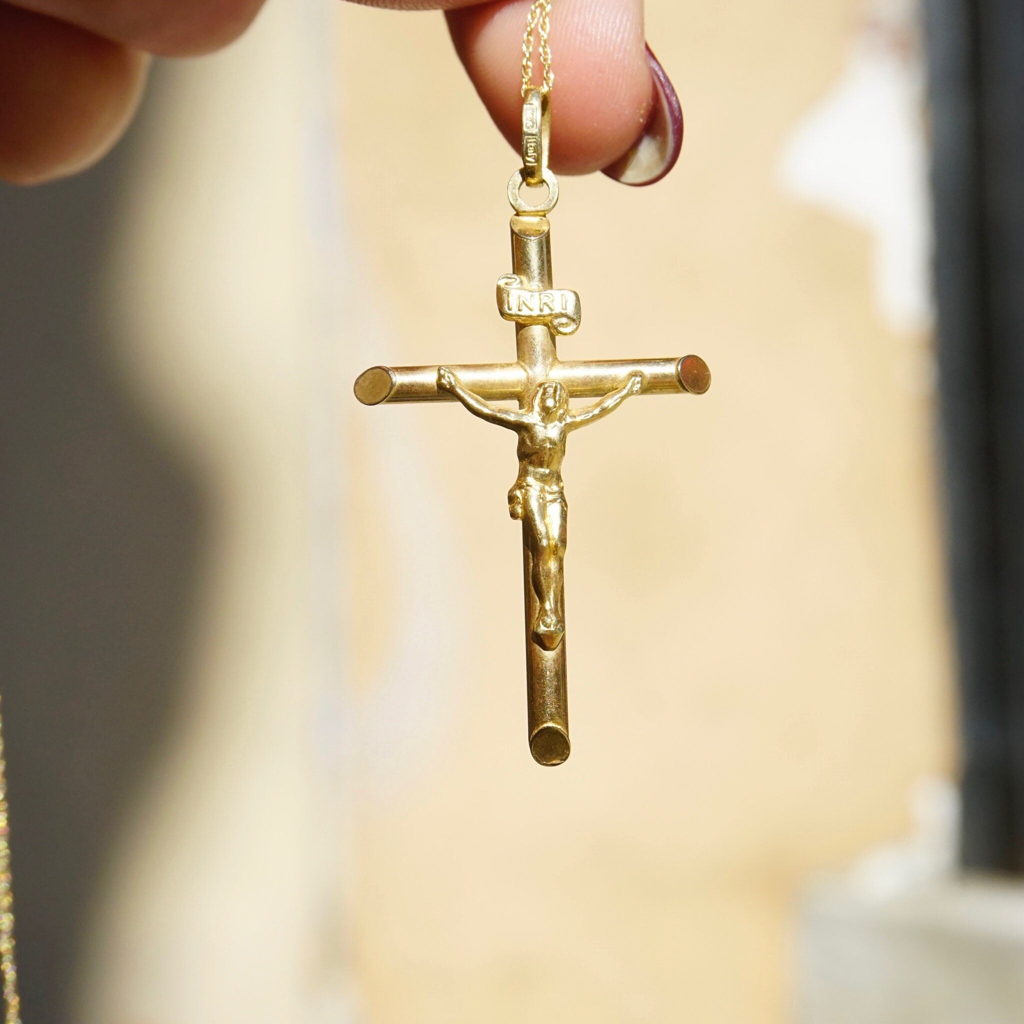 Hand holding a vintage 14K yellow gold INRI crucifix pendant necklace, an Orthodox cross pendant made in Italy.