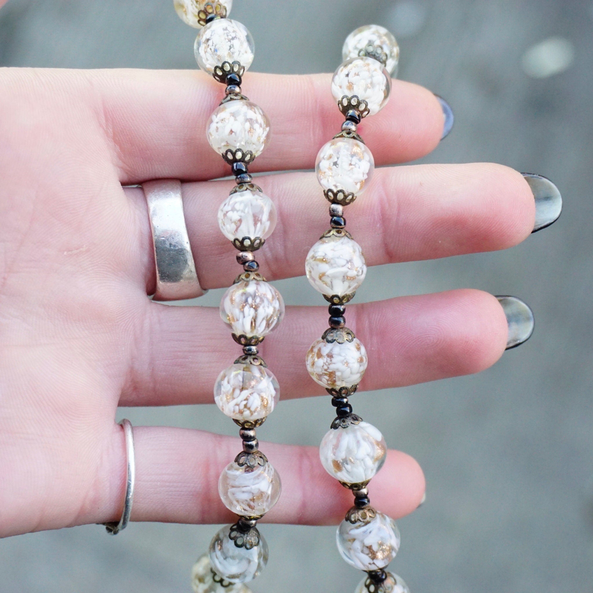 Vintage Italian Murano glass bead choker necklace with clear and white wedding cake beads held in a person's hand