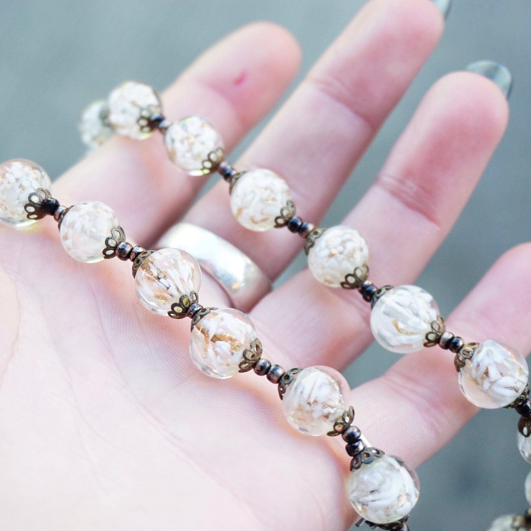 Vintage Italian Murano glass wedding cake bead choker necklace with clear and white beads held in a person's hand