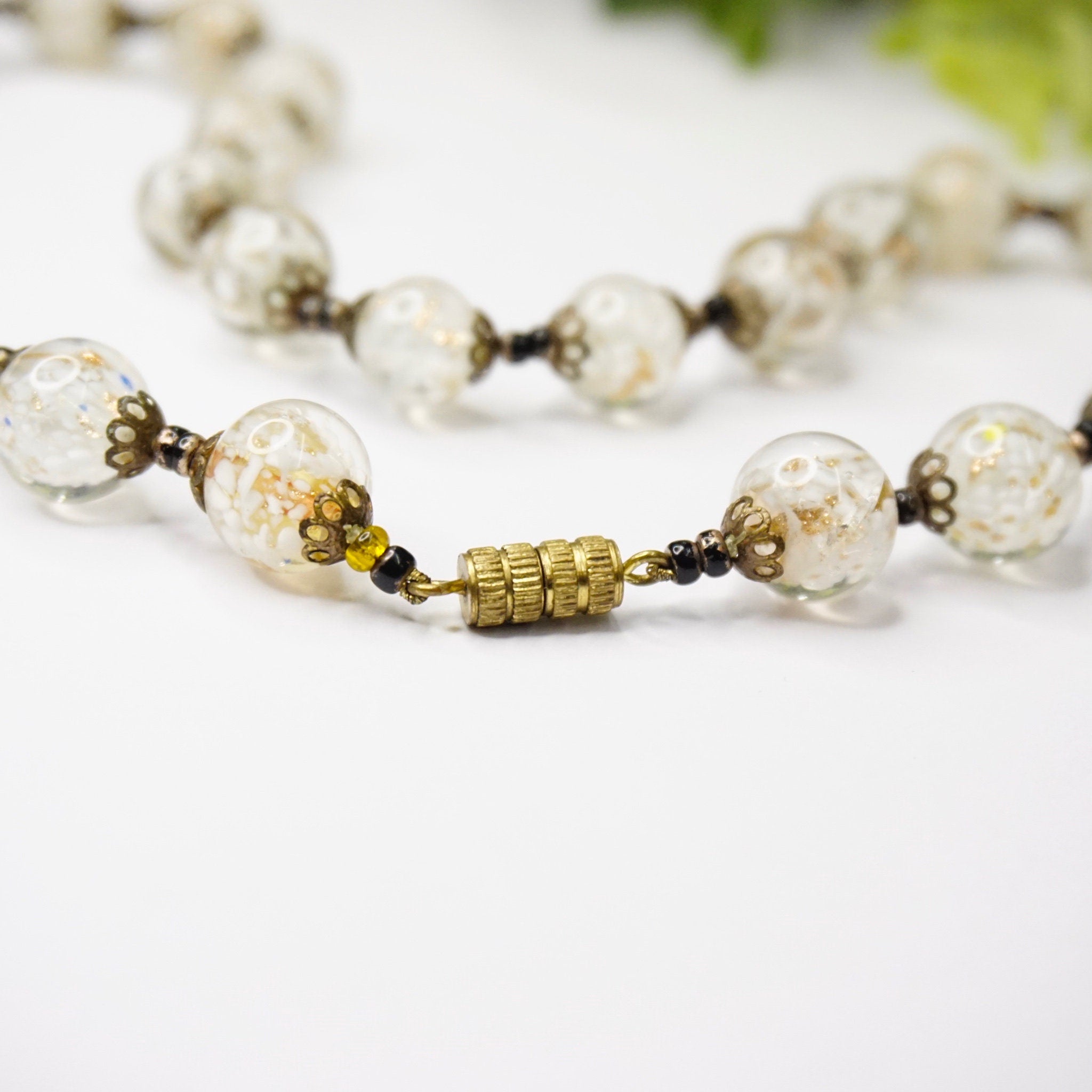 Vintage Italian Murano glass bead choker necklace with clear and white wedding cake beads strung on gold tone metal links, photographed on white background.