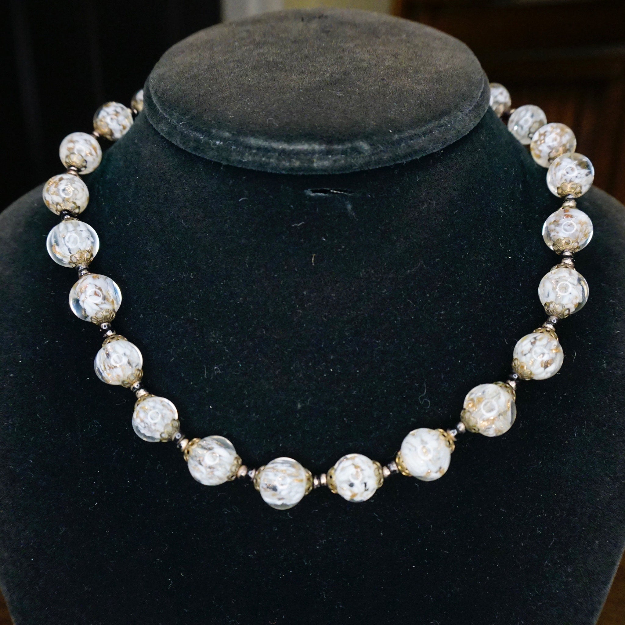 Vintage Italian Murano glass bead choker necklace with clear and white wedding cake style beads on a dark velvet display bust.